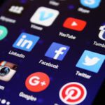 Close-up of a smartphone screen showing various social media app icons such as Facebook and Twitter.